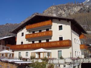 a large white building with wooden balconies in front of a mountain at Casa Martinelli Holiday Home in Valdidentro
