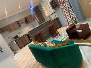 a living room with a green couch and a piano at nostiQ homes in Kampala