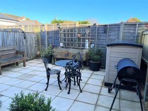 a patio with chairs and a table and a grill at 2 Brunswick Terrace in Sandown