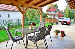 un patio con mesa y sillas en una terraza en R Cottage Jacuzzival en Balatonfenyves