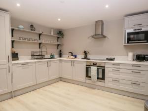 a kitchen with white cabinets and stainless steel appliances at Grizedale in Kendal