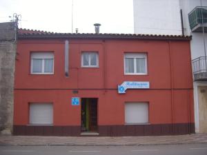 un bâtiment rouge avec une pancarte sur celui-ci dans l'établissement Hostal Cassa, à Cassà de la Selva