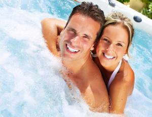 a man and a woman in a hot tub at R Cottage Jacuzzival in Balatonfenyves