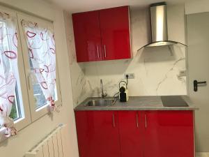 eine Küche mit roten Schränken, einem Waschbecken und einem Fenster in der Unterkunft Apto. BLAIA in Irún
