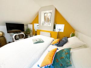 a bedroom with two white beds and a television at CHAMBRE APPARTEMENT in Roscoff