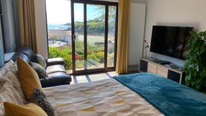 a living room with a bed and a large window at Portmellon Cove Guest House in Mevagissey