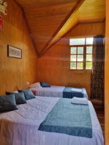 two beds in a room with wooden walls at Elfen hospedaje familiar in Oxapampa
