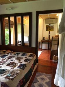 a bedroom with a bed in a room with windows at Bulunburi Resort in Ban Pong