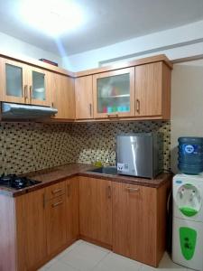 a kitchen with wooden cabinets and a sink and a microwave at Apartemen Bassura City by Globy Property in Jakarta