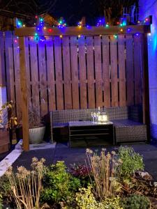 uma cerca de madeira com um banco num jardim à noite em The Mews 2 bedroom with private parking em Oban
