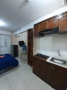 um quarto com uma cozinha com um lavatório e uma cama em Apartemen Bassura City by Globy Property em Jakarta
