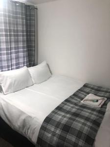 a white bed with a plaid blanket on it at Macpherson House in Luton