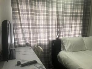 a bedroom with a bed and a curtain with a remote control at Macpherson House in Luton
