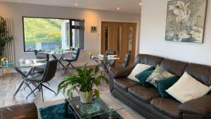 a living room with a brown leather couch and tables at Portmellon Cove Guest House in Mevagissey