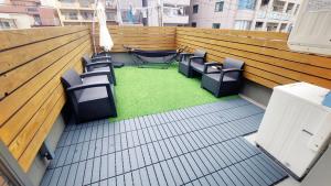 a balcony with chairs and a green floor at Poly Hostel 2 Namba in Osaka