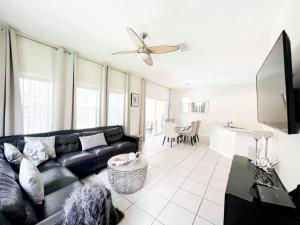 uma sala de estar com um sofá preto e uma televisão em Resort Home, Private Pool Orlando Disney sleeps12 em Kissimmee