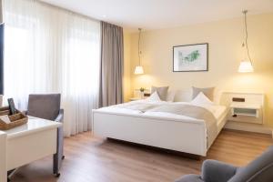 a bedroom with a large white bed and a desk at Hotel Deutscher Hof in Trier