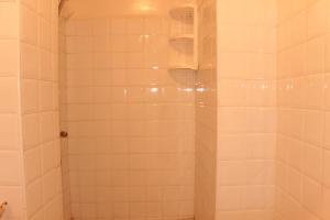 a bathroom with a shower with white tiles at Asunfou : Appartement d'apaisement in Mirleft +37 photos