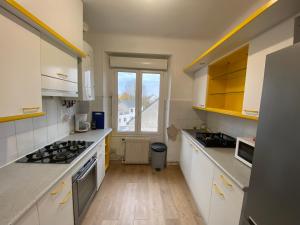une cuisine avec des comptoirs blancs et une fenêtre dans l'établissement Appartement T4 Cité Cardaillac, Parking Privé, Wifi, à Rodez
