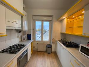 eine Küche mit weißen Schränken, einem Waschbecken und einem Fenster in der Unterkunft Appartement T4 Cité Cardaillac, Parking Privé, Wifi in Rodez