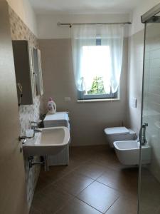 a bathroom with two sinks and a toilet and a window at Le Dune per 4 - Appartamento con piscina in Silvi Paese +12 photos