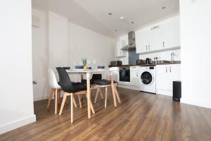 a white kitchen with a table and chairs at Plush 2-bedroom apartment Coventry city center in Coventry