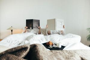 a person laying in bed reading a book at Wex Hotels in Fredrikstad