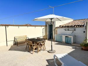 un patio con una mesa y una sombrilla en Calauriia Apartments Marzamemi, en Marzamemi