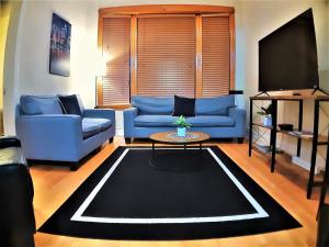 una sala de estar con 2 sofás azules y una mesa. en The Roscoe Village Guesthouse, en Chicago
