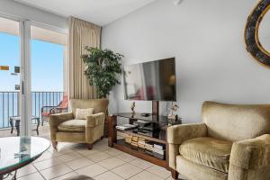 a living room with a tv and two chairs and a table at Majestic Sun 1012A in Destin