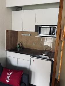 una pequeña cocina con armarios blancos y microondas en Studio 4 personnes - accès direct remontées mécaniques, en Les Contamines-Montjoie