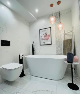 La salle de bains blanche est pourvue d'une baignoire et de toilettes. dans l'établissement SOL, à Oviedo
