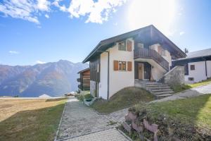a house on a hill with mountains in the background at Serenella Apartment in Riederalp