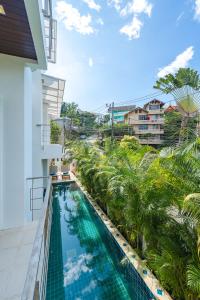 uma piscina de beiral infinito na varanda de um edifício com palmeiras em White Villa Patong em Praia de Patong