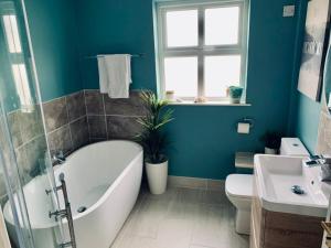 a bathroom with a tub and a toilet and a sink at Ballycastle Holiday Home in Ballycastle +13 photos