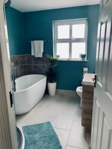 a bathroom with a tub and a toilet and a window at Ballycastle Holiday Home in Ballycastle