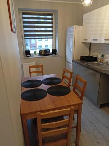 a kitchen with a wooden table with chairs and a kitchen with a refrigerator at Apartament Blondynka Miasto Soli Bochnia in Bochnia
