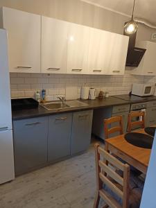 a kitchen with white cabinets and a wooden table at Apartament Blondynka Miasto Soli Bochnia in Bochnia