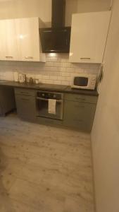 a kitchen with a black stove and white cabinets at Apartament Blondynka Miasto Soli Bochnia in Bochnia