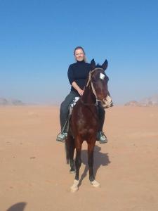 a woman riding a horse in the desert at Sunset Mountain in Wadi Rum