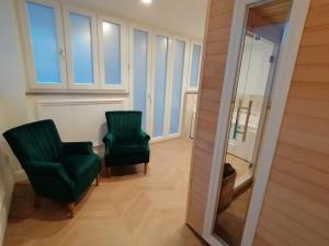 un couloir avec deux chaises vertes et un miroir dans l'établissement Hotel XBusiness, à Nola