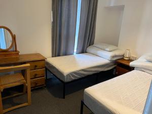 a room with two beds and a dresser and a mirror at Scotland Beds in Dundee