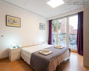 バレンシアにあるSuites Rooms Valenciaの白いベッドルーム(ベッド1台、大きな窓付)