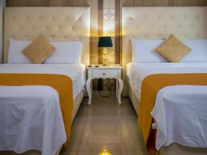 a hotel room with two beds and a table with a lamp at Hotel Boutique The Royalty in Guayaquil