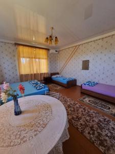 una habitación con 2 camas y una mesa con un jarrón en Guesthouse at Oleg's Zolotoy Bereg, en Gudauta