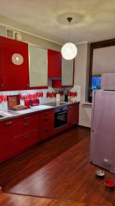 uma cozinha com armários vermelhos e um frigorífico de aço inoxidável em Na Kazimierza em Poznań