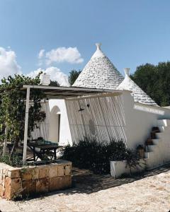 una pequeña casa blanca con mesa y techo en Fikus - the Apulian B&B, en Ceglie Messapica