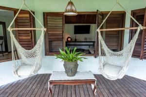 two hammocks in a room with a table and a plant at Villa Iamani in Arraial d'Ajuda