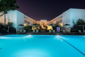 a swimming pool in front of a building at night at E-GEO Easy Living Resort in Marmari