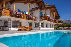 a villa with a swimming pool in front of a house at Garni Petra in Selva di Val Gardena